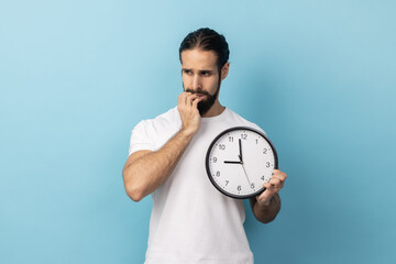 Portrait of impatient nervous man with beard wearing white T-shirt sitting biting her nails holding...