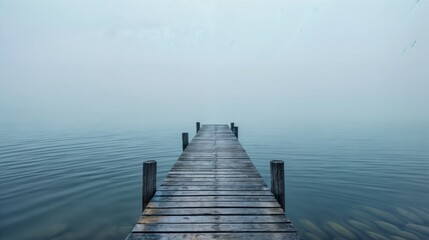 Wooden dock extending into calm, misty lake