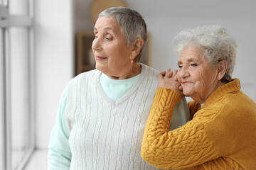 Senior female friends looking in window at home, closeup
