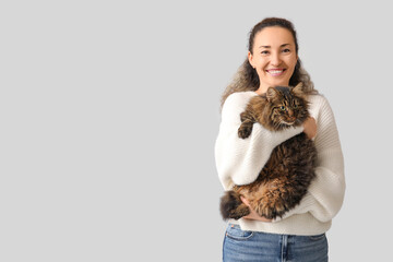 Happy mature woman with cute cat on grey background © Pixel-Shot