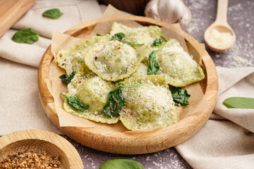 Plate of tasty ravioli with cheese on grey background