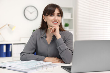 Portrait of smiling secretary at table in office