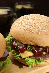 Wooden board with delicious cheeseburgers against blurred background, closeup