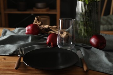 Set of clean dishware, ripe red apples and flowers on dining table indoors