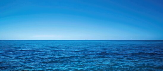 Obraz premium Vivid blue ocean under a clear sky with room for text.