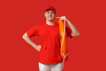 Male lifeguard with ring buoy and whistle on red background