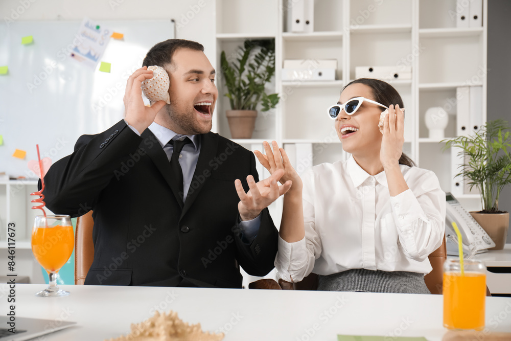 Poster Happy office workers sitting at table and listening seashells in office. Summer vacation concept