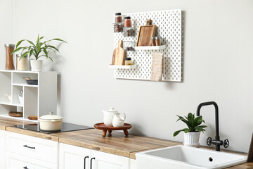 Stylish light kitchen with pegboard and kitchenware