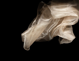 Yellow gold organza fabric flying in curve shape, Piece of textile Yellow gold organza fabric throw fall in air. Black background isolated, dark shading environment