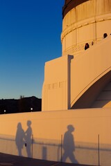 Fototapeta premium Abstract shapes of peoples shadows cast onto the building of the Griffith Observatory at sunset, Los angeles, California, USA.