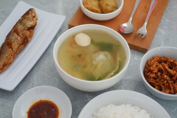 Creamy soup in a white bowl, with delicious side dishes