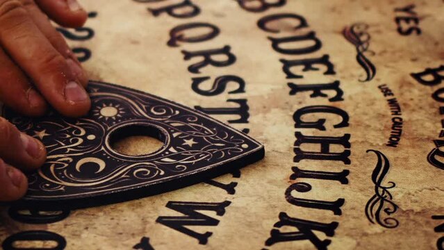 Man is playing with Spiritual Witchcraft Ouija Board
