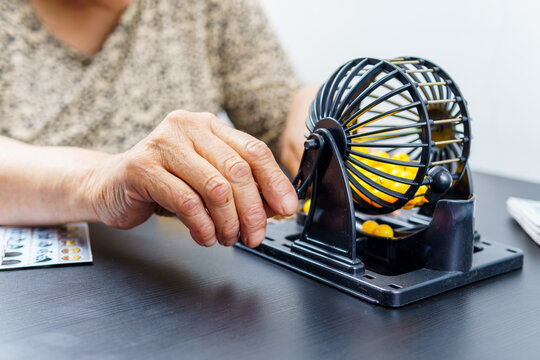 a woman who is playing bingo alone, shuffling some ballots with a bingo machine.