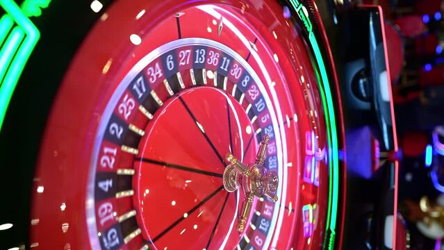 Electronic casino roulette slowly spinning, red neon light. Vertical video for social networks