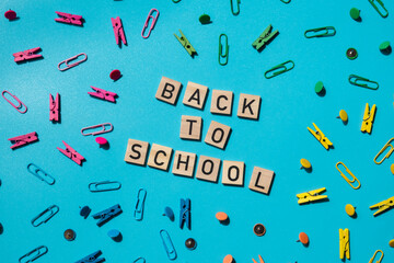 Educational greeting announcement for students and teacher. Saying BACK TO SCHOOL text on wooden blocks on creative vivid background with stationery supplies around. Concept of new school year Top