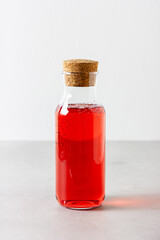 Red berries and fruits drink in the glass bottle on the light background.