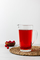 Red color drink in the glass jug on gray background.