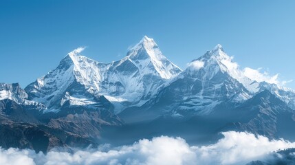 Snow covered mountain peaks shrouded in misty clouds under a clear blue sky
