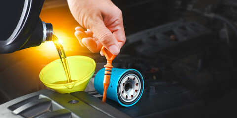 Car maintenance service , Pouring engine oil into a funnel with spare parts for engine maintenance , copy space on dark background for text , Car repair garage business concept