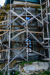 Fototapeta premium Wooden scaffolding near the old building. Ancient building restoration