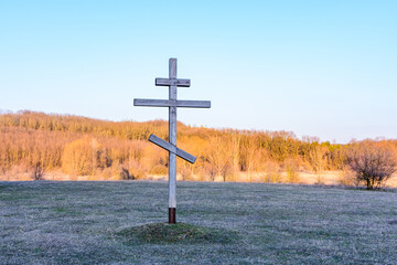 Old wooden cross on a meadow against sky