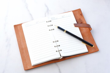 リング式のシステム手帳を開いてデスクワークをしているイメージ
