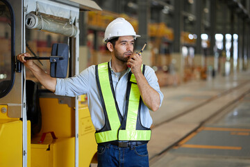 Engineer or worker talking on walkie talkie with a car in the factory