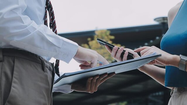 Insurance agent writing on clipboard while examining car after accident claim being assessed and processed