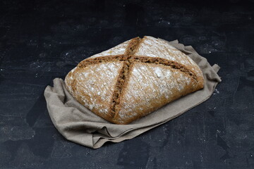 Sliced homemade sourdough rye bread with rye flour on black textured background. Top view or flat-lay. Low key