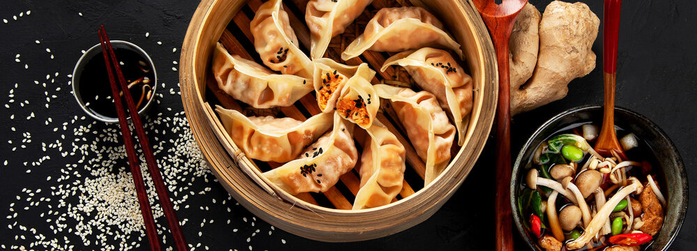 Asian traditional cooked food. Damplings, shrimps and mushrooms soup on black background.Asian traditional cooked food. Damplings, shrimps and mushrooms soup on black background