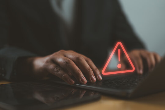 Businessman or it staff, programmer, developer using computer laptop with triangle caution warning sign for notification error and maintenance concept.