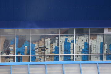 The storage room is full of neatly stacked boxes on shelves, with a window for light