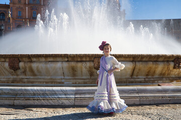 Girl dancing flamenco, posing looking at camera, in typical flamenco costume next to spectacular...