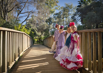 Four girls dancing flamenco, posing looking at the camera, in typical flamenco dress, on a wooden...