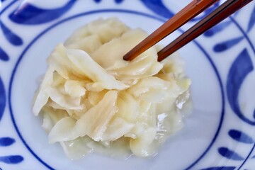 A close up shot of some pickled ginger with wooden chopsticks.