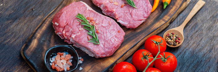 Banner Raw meat beef steak organic fresh ingredient on wooden board table background in kitchen with rosemary, salt, garlic, tomato, olive oil. Meat beef on wooden plate for beefsteak with copy space
