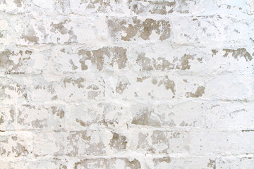 The texture of flaky whitewash on a brick wall. An old white wall with brickwork.