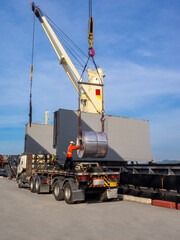 Loading of hot rolled steel coils on board of cargo ship using braided wire slings and heavy crane.