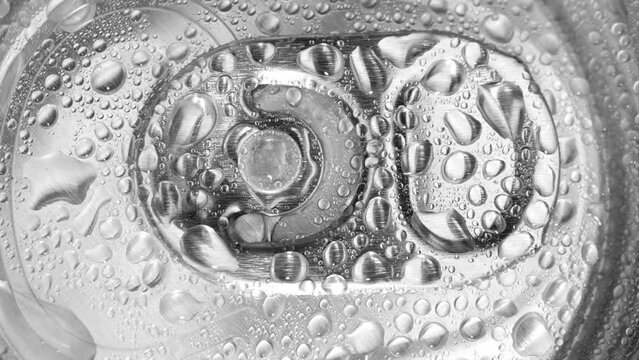 The metallic sheen of the can's lid catches the light, adorned with scattered droplets like jewels. A tantalizing invitation to quench your thirst awaits beneath the tab. Metallic  background.
