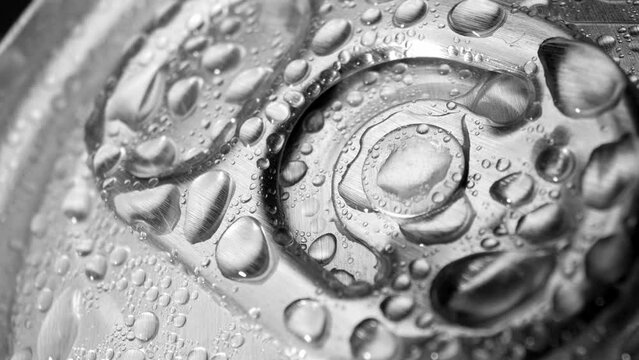 A close-up reveals the tantalizing sight of water droplets adorning the aluminum lid of the can, hinting at the refreshing drink within. The pull tab beckons for exploration. Beverage background.
