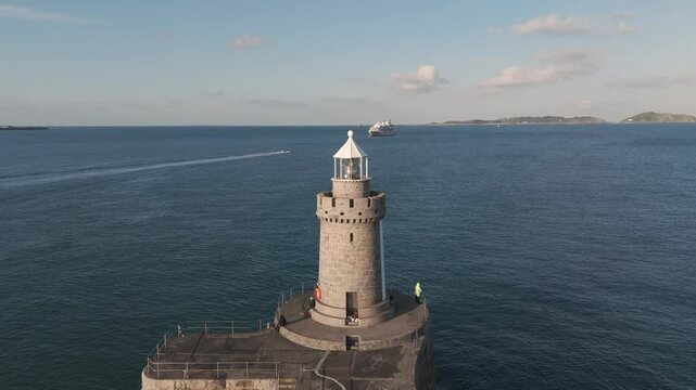 Reveal of lighthouse and breakwater Castle Cornet St Peter Port, Guernsey with cruise ship in the background on bright sunny day