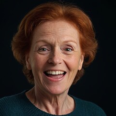 Фn older woman with red hair and fair skin. She smiles and looks directly into the camera. The woman is wearing a green sweater. The background of the photo is dark, which highlights the woman's face