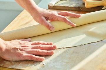 Step-by-step cooking process. Roll out the dough into a thin layer using a wooden rolling pin