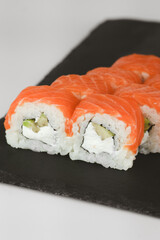Close-up of salmon and cream cheese sushi rolls on a black slate plate