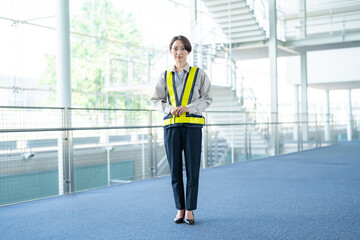 室内に立つ作業着を着た女性