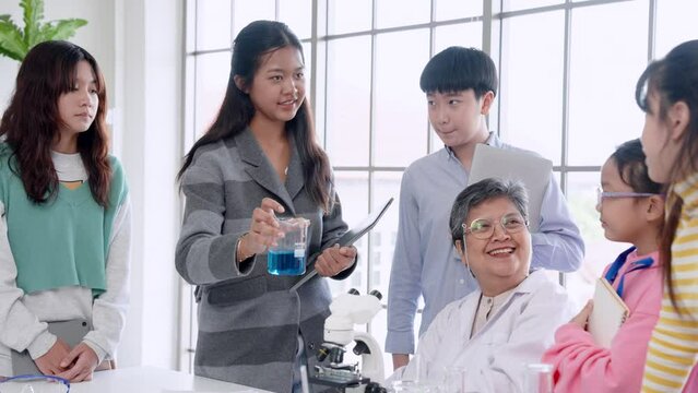 Science teacher Introducing female students in the classroom Let the microscope be used during elementary school science lessons. Groups of students try to look at microorganisms through microscope.