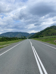 Road in the mountains. Road in cloudy weather in mountainous terrain. Picturesque nature in the Altai Mountains.