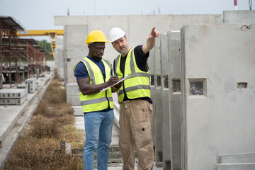 Portrait African engineer man working with caucasian engineer man at precast cement outdoor factory	