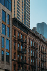 Historic New York City buildings with fire escapes and modern high-rise in background