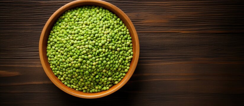 A top view of a wooden bowl containing green moong dal also known as mung bean against a wooden background Copy space image